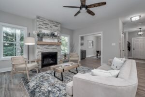 Modern living room with a fireplace, neutral colored furniture, hardwood floors, and large windows.