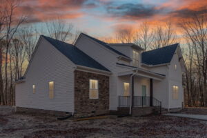 A modern two-story house with white and brick siding under a vibrant sunset sky.