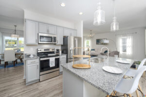 Modern kitchen with stainless steel appliances, granite countertops, and pendant lights, opening to a dining area.
