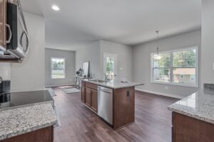 Modern kitchen with granite countertops, stainless steel appliances, and hardwood flooring in a home with ample natural light.