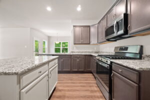 Modern kitchen interior with white and dark wood cabinets, granite countertops, and stainless steel appliances.