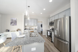Modern kitchen interior with stainless steel appliances, granite countertops, and pendant lights.
