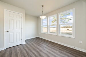 Bright room with large windows, wood flooring, a white door, and a hanging light fixture.