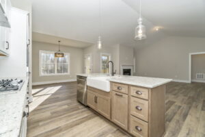Modern kitchen with wooden cabinets, granite countertops, and stainless steel appliances, featuring a large central island and pendant lighting.