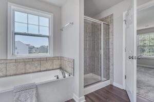Modern bathroom with a corner bathtub, glass shower stall, and a window overlooking a residential area.