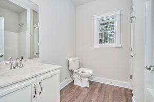 Modern bathroom interior with white walls, a single window, vanity with sink, and a toilet.
