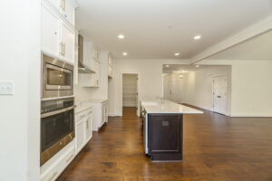 Modern kitchen with white cabinetry, stainless steel appliances, a central island, and hardwood floors.