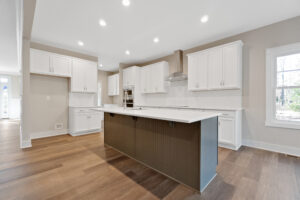 A modern kitchen with white cabinetry, stainless steel appliances, a large center island, hardwood flooring, and recessed lighting.