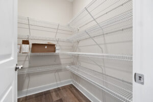 Image of an empty pantry closet with white wire shelving along the side and back walls. There are some brown boxes and a small white item on one of the shelves.