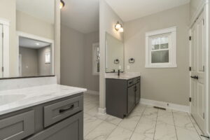 Modern bathroom with two vanities, large mirrors, and white marble countertops. Neutral gray and beige tones.