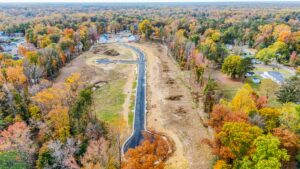 Aerial view of Poplar Village, a residential neighborhood under construction, surrounded by autumn trees.
