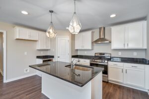 Modern kitchen with sleek white cabinets, black countertops, island sink, and stainless steel appliances. Pendant lights illuminate the space like a well-coordinated dispatch station, ensuring functionality meets style in every culinary experience.