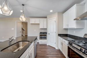 Carter-designed modern kitchen with white cabinets, dark countertops, stainless steel appliances, and geometric light fixtures.