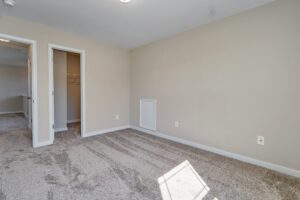 The empty room features beige walls and a gray carpet, with two open doors leading to a closet and another room. It's almost as if Carter was at the dispatch station, meticulously organizing each detail before moving on to his next task.