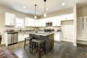 Modern Westwood kitchen with white cabinets, dark island, stainless steel appliances, and pendant lights over the island, resembling a sleek dispatch station in its efficiency and design.