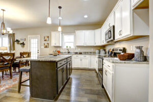 Modern kitchen with white cabinets, granite countertops, and a center island, offering an open view to the dining area. Located in the charming Westwood neighborhood, this space is perfect for both intimate dinners and lively gatherings.