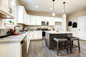 A modern kitchen in the heart of Westwood features a marble island, wooden stools, white cabinets, and sleek stainless steel appliances.