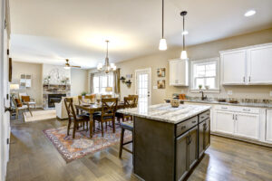 Spacious open-concept kitchen and dining area with island, white cabinets, and cozy living room featuring a stone fireplace, perfectly located in the heart of Westwood.