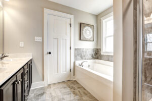 Modern bathroom with a white bathtub, vanity with sink, beige walls, and a decorative wall art piece that adds a touch of Westwood elegance.