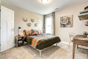 Modern bedroom with a Westwood double bed, colorful bedding, abstract wall art, and a wooden desk paired with a chair.