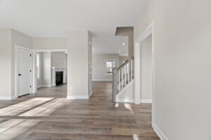Lot 19 offers a spacious empty room with wooden floors, a staircase, and large windows that flood the space with natural light. Nestled in the serene Autumn Hill neighborhood, this inviting setting perfectly blends elegance and tranquility.