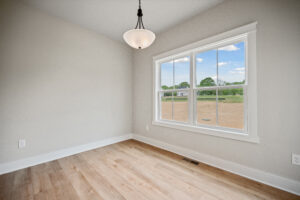 The empty room in Poplar Village features light wood floors, neutral walls, and a white-trimmed window offering views of the Stafford yard, complemented by a simple overhead light fixture.