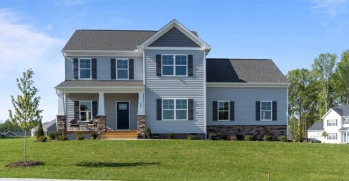 Two-story grey house in Poplar Village, with a porch and manicured lawn, set against trees and a clear Rowland sky.