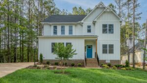 Nestled in Poplar Village, this two-story white house features a charming blue door, surrounded by trees and a well-kept lawn, offering the perfect retreat in Albany.
