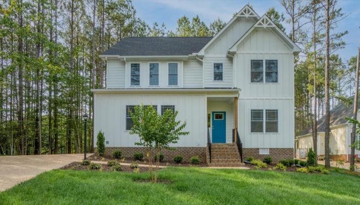 Nestled in Poplar Village, this two-story white house features a charming blue door, surrounded by trees and a well-kept lawn, offering the perfect retreat in Albany.