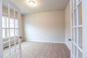 Bright, empty room in one of the new homes in Richmond VA with beige carpet, cream walls, French doors, and ample light.