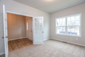 Bright empty room with beige carpet, large window, and double glass doors—perfect for new homes in Richmond VA.
