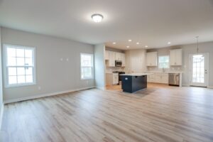 Modern open-concept kitchen and living area in new homes in Richmond VA, featuring wood floors and bright natural light.