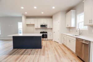 Modern kitchen in new homes in Richmond VA, with white cabinets, stainless appliances, and a large dark island.