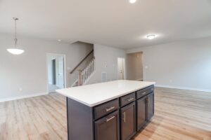 Modern kitchen with island, hardwood floors, and open living space in stylish new homes in Richmond VA.