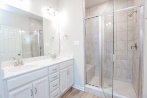 Bright bathroom with double sinks and a glass-enclosed shower found in stylish new homes in Richmond VA.