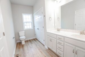 Bright bathroom with white cabinets, double sink, and wood floor—perfect for new homes in Richmond VA.