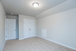 Empty room with beige carpet, white walls, and double closet doors in new homes in Richmond VA.