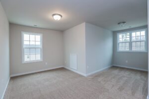 Empty room with beige carpet, two windows, and a dividing wall—ideal for new homes in Richmond VA.