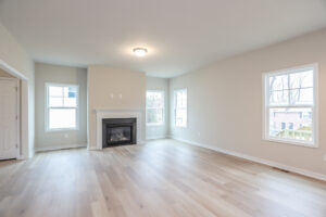 Empty living room in Lot 32, Poplar Village with light wood floor, beige walls, fireplace, and several windows.