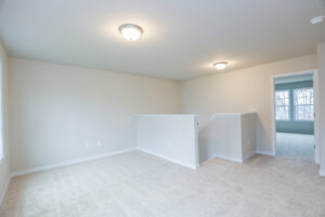 Bright, empty room with beige carpet, light gray walls, and two ceiling lights in Poplar Villages Lot 31.