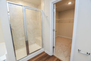 Poplar Villages Lot 31 boasts a bathroom with a glass shower, adjacent walk-in closet, and wooden floor.
