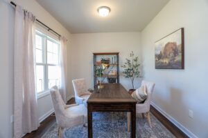 Bright home office in one of the new homes in Richmond VA, with two chairs, a wooden desk, shelves, and art on the wall.