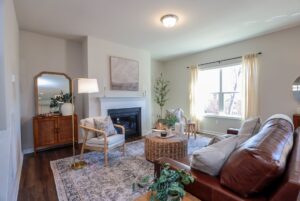 Bright living room in new homes in Richmond VA with a leather sofa, fireplace, armchair, and large window.