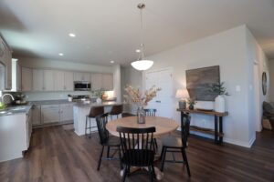 Modern kitchen and dining area in new homes in Richmond VA with round wooden table, black chairs, and neutral decor.