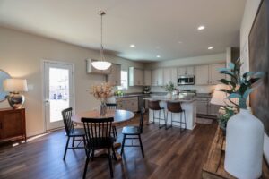 Modern kitchen and dining area in new homes in Richmond VA, featuring wooden floors, round table, and gray cabinets.