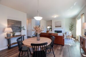 Open living and dining area in new homes in Richmond VA, featuring a round wooden table, black chairs, and a brown sofa.