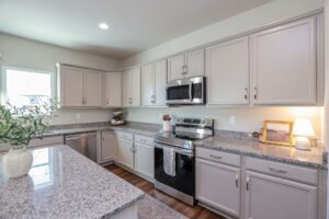 Modern kitchen with gray cabinets, granite countertops, and stainless appliances found in new homes in Richmond VA.