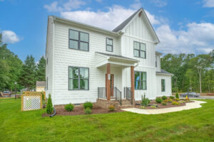 Nestled in the charming Poplar Village, this modern two-story white house features a landscaped front yard under a serene blue sky.