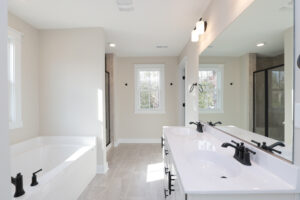 Modern bathroom in Poplar Village with a double sink, large mirror, bathtub, and shower. White and beige color scheme.