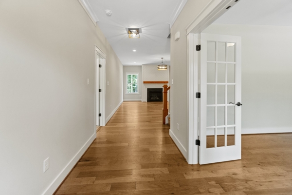 Interior view of a bright hallway with wood floors, white walls, and a glass-paneled door leading to the inviting living space of Scotchtown Estates.